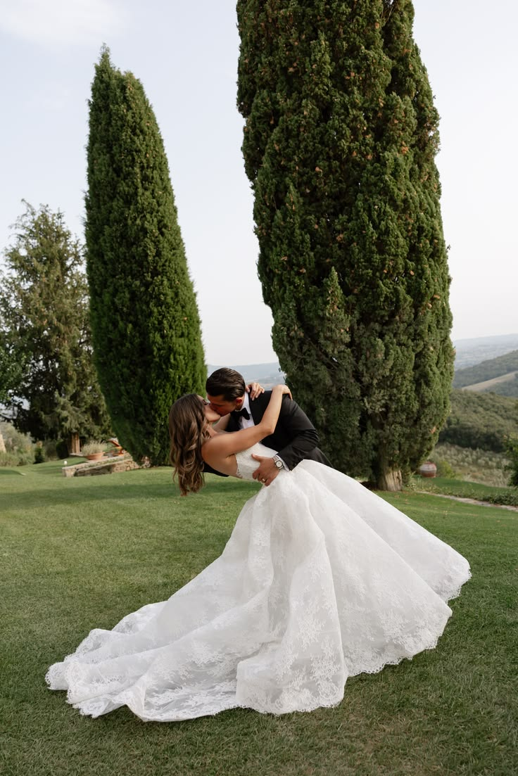 A wedding couple sharing a kiss in a garden framed by tall cypress trees